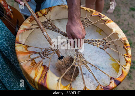Eine Nahaufnahme einer Hand, die eine traditionelle native Drum und drumstick, während einer Musik Feier in einem Park Stockfoto