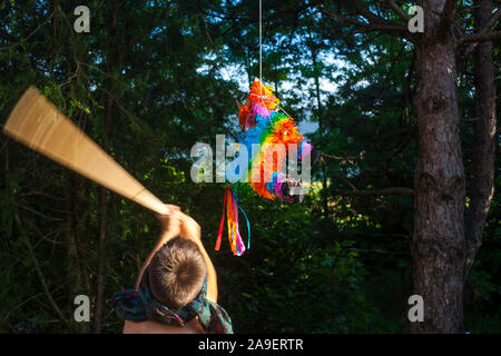 Ein Junge mit verbundenen Augen schlagen ein Pinata mit einem Stock Stockfoto