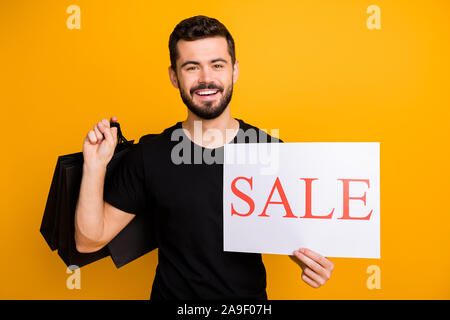 Foto der tausendjährigen Kerl halten viele shopping Packs war angenehm niedrigen Preisen einkaufen, Papier Karte mit Verkauf verkünden tragen schwarze T-Shirt isoliert Stockfoto