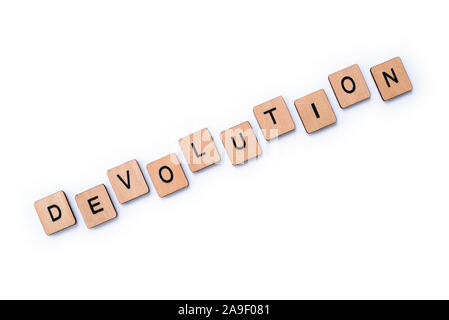 Das Wort DEVOLUTION, Dinkel mit hölzernen Buchstabensteine über einen weißen Hintergrund. Stockfoto