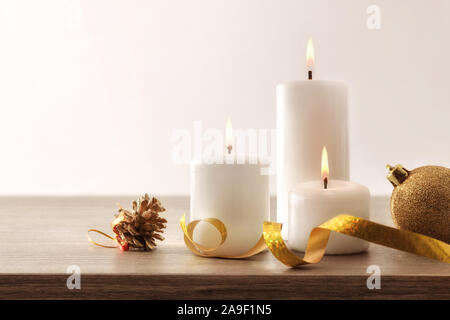 Einfache Weihnachten Komposition mit drei brennenden Kerzen und Weihnachten Elemente auf Holztisch und isolierten Hintergrund. Vorderansicht. Horizontale Zusammensetzung Stockfoto