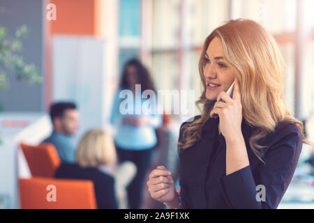 Frau spricht auf Handy vor Team Stockfoto