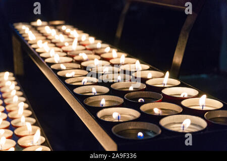Beleuchtete tee Kerzen in einer Reihe auf dunklem Hintergrund Stockfoto