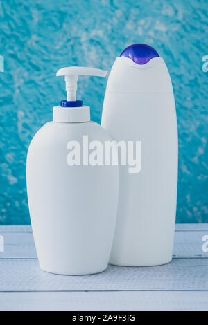 Die zwei weißen Plastikflaschen auf blauem Hintergrund. Hygienische Konzept. Eine Gruppe von sauberen Behältern auf Türkisfarbenem Hintergrund. Stockfoto