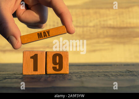19. Mai. Tag 19 Monat, Kalender auf einem holzwürfel. die Hand einer Frau wird der Name des Monats auf die Zahl des Monats auf einer hölzernen Hintergrund spri Stockfoto