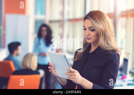 Portrait von Happy Geschäftsfrau Holding digital Tablet im Büro stand vor der Kollegen diskutieren Hintergrund Stockfoto