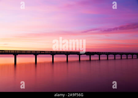 Fußgängerbrücke im Meer bei Sonnenuntergang Stockfoto