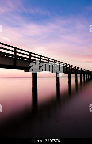 Fußgängerbrücke im Meer bei Sonnenuntergang Stockfoto