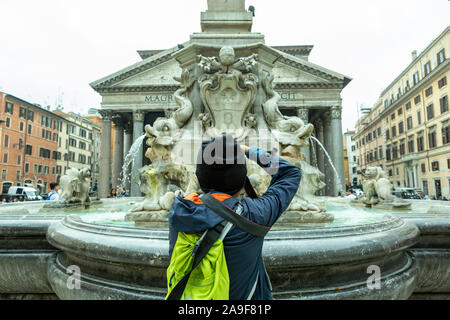 Ein Tourist macht ein Foto von einem Brunnen auf der Piazza del Pantheon mit dem Pantheon im Hintergrund Stockfoto