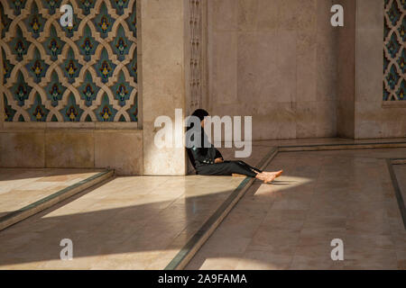 Lokale Frau sitzt barfuß in im Vorraum der Hassan-II. Moschee, Casablanca, Marokko Stockfoto