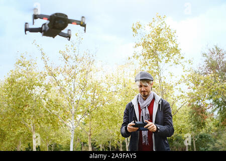 Junger Mann mit Fernbedienung Lernen zu fliegen Quadcopter Drone Stockfoto