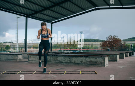 Sportlerin springen auf einem agility Ladder Stockfoto