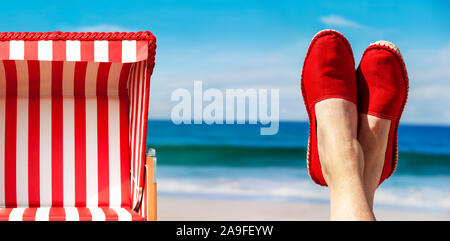 Beine mit rotem Tuch Schuhe vor der Strand und das Meer. Stockfoto