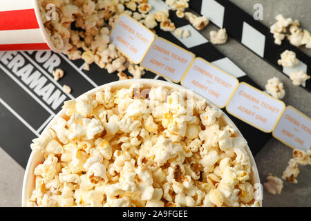 Klappe, Tickets und Eimer mit Popcorn auf grauem Hintergrund, Ansicht von oben