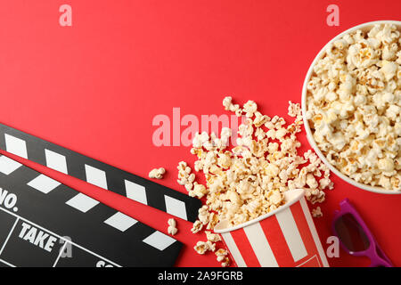 Flach. Eimer mit Popcorn, 3D-Brillen und Klappe auf rotem Hintergrund Stockfoto