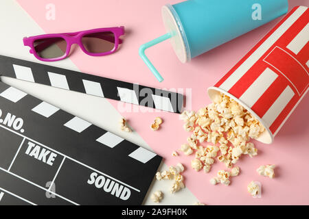 Eimer mit Popcorn, Klappe, Trinken und 3D-Brille auf zwei ton Hintergrund Stockfoto