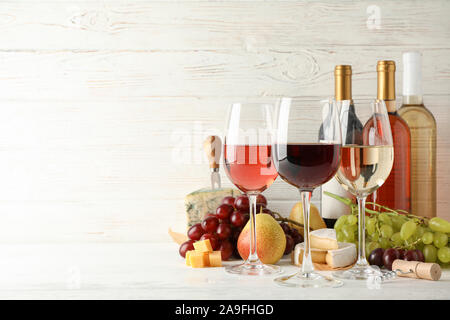 Früchte, Käse, Flaschen und Gläser mit verschiedenen Wein auf weißem Hintergrund, Platz für Text Stockfoto