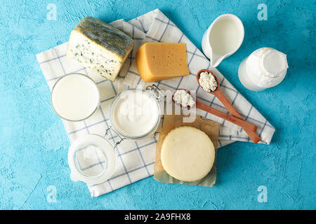 Frische Milchprodukte und Küchentuch auf blauem Hintergrund, Ansicht von oben Stockfoto