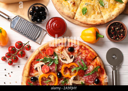 Leckere Pizza und Zutaten auf weißem Holz- Hintergrund, Ansicht von oben Stockfoto