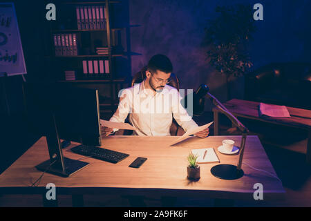 Foto von nachdenklich ernsten zuversichtlich Sales Manager vergleichen Bewertungen Erträge Gewinn der vorhergehenden Periode mit aktuellen am Desktop mit Nacht Stockfoto