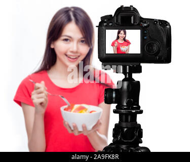 Asiatische Lebensmittel vlogger mit Obstsalat hinter der Kamera, social media Produktion Konzept Stockfoto