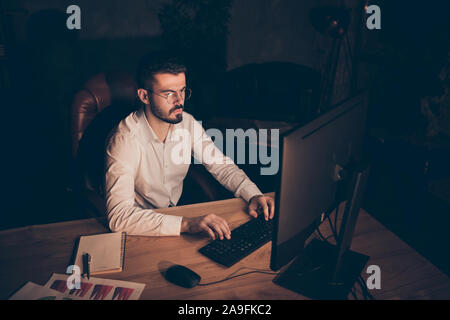 Foto von Interesse konzentrierte sich konzentriert man am Desktop versuchen Bericht notwendig an seinen Arbeitgeber morgen zu Arbeiten bei Nacht zu sitzen Stockfoto
