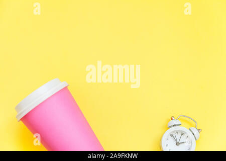 Einfach flach Design rosa Papier Kaffeetasse und Wecker auf Gelb bunte trendy Hintergrund isoliert. Takeaway trinken Frühstück trinken. Guten Morgen aufwachen wach Konzept. Ansicht von oben kopieren Raum Stockfoto