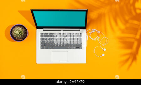 Laptop auf eine helle gelbe Schreibtisch und Palmblättern Schatten, Sommer Ferien Zeit Konzept Stockfoto