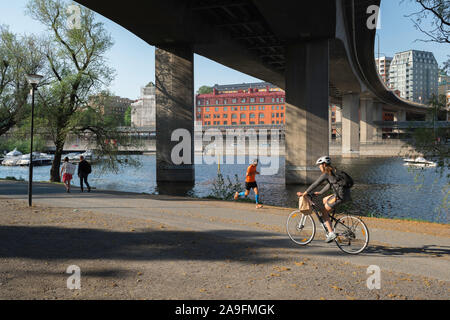 Stockholm Kungsholmen, Aussicht im Sommer des schwedischen Volkes Laufen und Radfahren unter der Brücke in der Barnhusbron Kungsholms Strand Park, Stockholm. Stockfoto