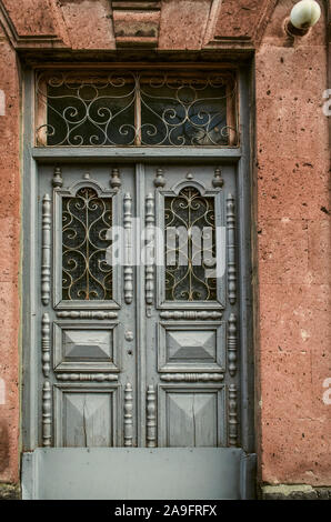 Eine doppelflügelige Tür mit geschnitzten Details ist mit Durchbrochenem abgedeckt schmiedeeisernen Stäben auf die Fenster der Tür an der Fassade der Stein b Stockfoto