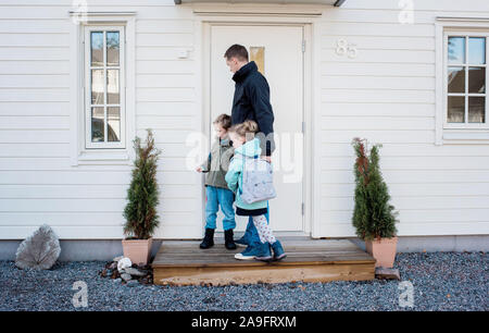 Vater, seine Kinder zur Schule Verriegelung der vorderen Klappe zu Hause Stockfoto