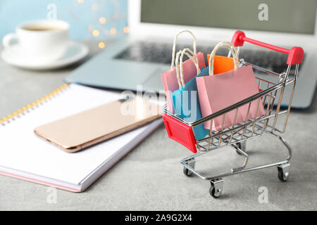 Zusammensetzung mit kleinen Warenkorb und Papiertüten auf grauem Hintergrund, Platz für Text Stockfoto