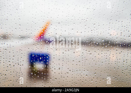 Blick aus einem Flugzeug Fenster in Wassertropfen bedeckt mit dem Flughafen verwischt. Stockfoto