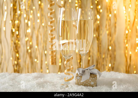 Champagner Gläser und Geschenk gegen Hintergrund mit goldenen Bändern, Platz für Text Stockfoto