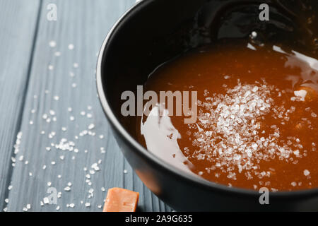 Schüssel mit gesalzen Karamell und Bonbons auf hölzernen Hintergrund, in der Nähe Stockfoto