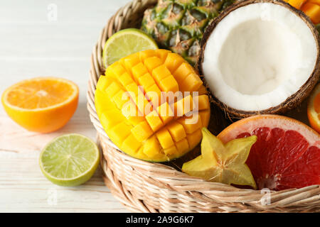 Weidenkorb mit exotischen Früchten auf weißem Hintergrund Holz, in der Nähe Stockfoto