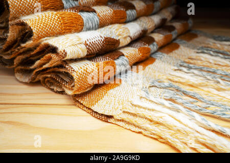 Gestapelte gestrickt Plaid mit Fransen. Strick Decke Stoff Textur mit einer komplexen Square verweben. Stockfoto