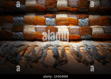 Gestapelte gestrickt Plaid mit Fransen. Strick Decke Stoff Textur mit einer komplexen Square verweben. Stockfoto