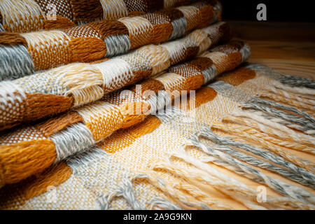 Gestapelte gestrickt Plaid mit Fransen. Strick Decke Stoff Textur mit einer komplexen Square verweben. Stockfoto