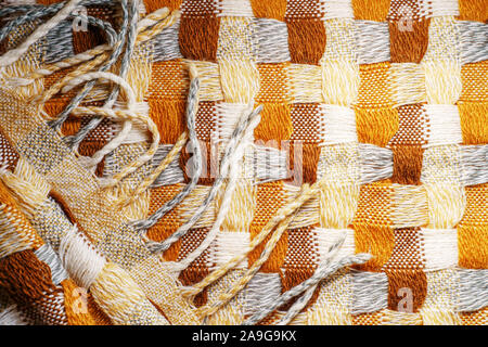 Gestrickte Plaid mit Fransen Hintergrund. Strick Decke Stoff Textur mit einer komplexen Square verweben. Stockfoto