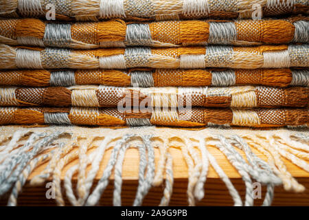 Gestapelte gestrickt Plaid mit Fransen. Strick Decke Stoff Textur mit einer komplexen Square verweben. Stockfoto
