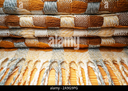 Gestapelte gestrickt Plaid mit Fransen. Strick Decke Stoff Textur mit einer komplexen Square verweben. Stockfoto
