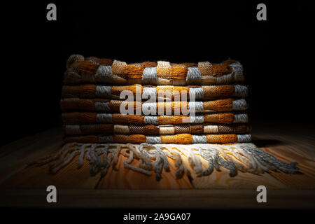 Gestapelte gestrickt Plaid mit Fransen. Strick Decke Stoff Textur mit einer komplexen Square verweben. Stockfoto