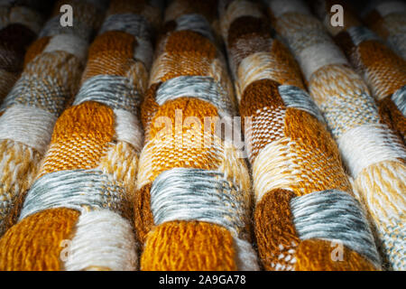 Gestapelte gestrickt Plaid Hintergrund. Strick Decke Stoff Textur mit einer komplexen Square verweben. Stockfoto