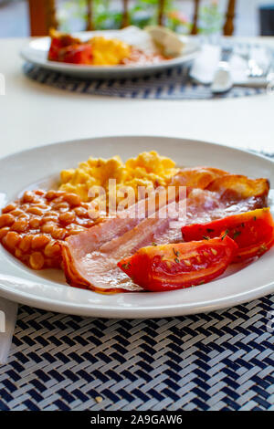 Englisches Frühstück mit gegrilltem Speck, Tomaten, Rührei und gebackene Bohnen in Tomatensoße in Spanien Stockfoto