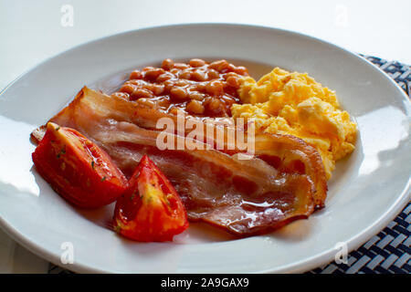 Englisches Frühstück mit gegrilltem Speck, Tomaten, Rührei und gebackene Bohnen in Tomatensoße in Spanien Stockfoto