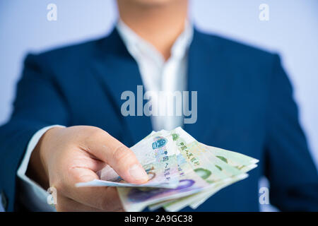 Geld in China halten an Hand der Mann trägt einen blauen Anzug CNY, Bezahlung, exchange Geld Volksrepublik China (VRC) auf weißem Hintergrund. Stockfoto