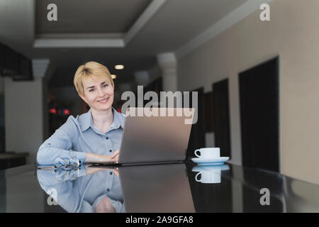 Elegante Frau blond ist mit Laptop im Cafe. Blogger arbeiten Konzept Stockfoto