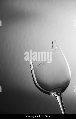 Studio closeup oblique Ansicht einer zerbrochenen Glas Wein vor der strukturierten Hintergrund mit weichen Licht dunkel Gradient monochrom. Stockfoto