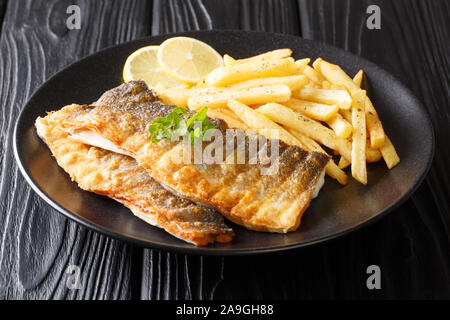Lecker gegrilltes Barschfilet mit Pommes Frites und Zitrone close-up auf einem Teller auf den Tisch. Horizontale Stockfoto